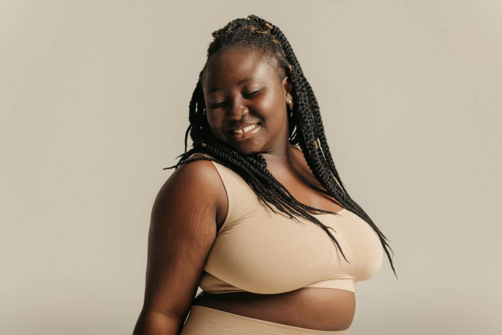 Attractive African plus size woman in underwear radiating self-love on studio background